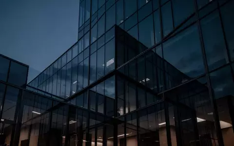 Moderne, minimalistische Glasfassade eines Bürogebäudes in der Dämmerung, die eine sichere und undurchdringliche Umgebung symbolisiert. - Foto: über boerse-global.de