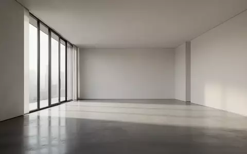 Ein minimalistischer, moderner Innenraum mit poliertem Betonboden und natürlichem Licht, das durch große Fenster fällt. - Foto: über boerse-global.de