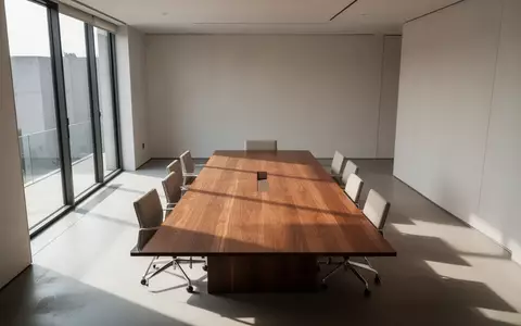 Ein minimalistischer, lichtdurchfluteter Konferenzraum mit einem leeren Holztisch in einer modernen BĂĽroumgebung. - Foto: ĂĽber boerse-global.de