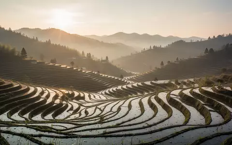 Eine ländliche Hügellandschaft mit Terrassenfeldern im warmen Licht der goldenen Stunde. - Foto: über boerse-global.de