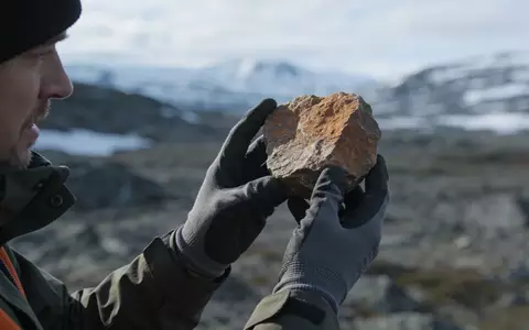 Geologe untersucht eine Gesteinsprobe in einer nordischen Landschaft. - Foto: über boerse-global.de