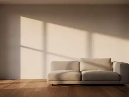 Ein minimalistisch gestalteter, lichtdurchfluteter Wohnraum mit schlichtem Sofa und klaren architektonischen Linien. - Foto: über boerse-global.de