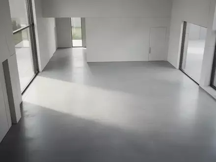 Ein minimalistischer, lichtdurchfluteter Raum mit klaren architektonischen Linien und einem polierten Betonboden. - Foto: über boerse-global.de