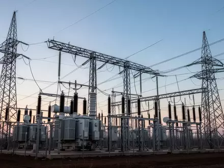 Ein modernes Umspannwerk mit Hochspannungstransformatoren und Stromleitungen vor einem weiten Abendhimmel. - Foto: über boerse-global.de