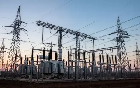 Ein modernes Umspannwerk mit Hochspannungstransformatoren und Stromleitungen vor einem weiten Abendhimmel. - Foto: über boerse-global.de