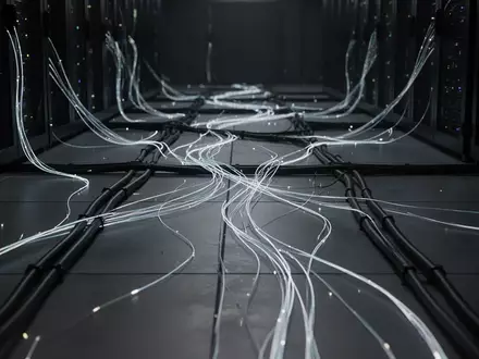 Abstrakte Darstellung von Glasfaserkabeln und Lichtleitern in einer dunklen, technologischen Umgebung. - Foto: über boerse-global.de