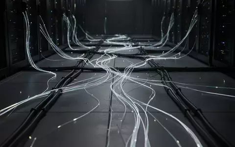 Abstrakte Darstellung von Glasfaserkabeln und Lichtleitern in einer dunklen, technologischen Umgebung. - Foto: über boerse-global.de