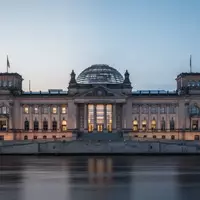 Das Reichstagsgebäude in Berlin bei Dämmerung, aufgenommen von der Spree aus mit Fokus auf die Architektur. - Foto: über boerse-global.de