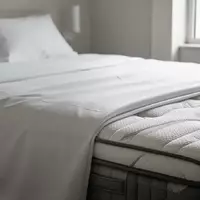 Nahaufnahme der Textur hochwertiger, weißer Bettwäsche und einer Matratzenkante in einem hellen, minimalistischen Schlafzimmer. - Foto: über boerse-global.de