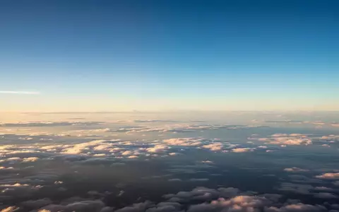 Ein weiter, klarer Himmel über einer dichten Wolkendecke, der die Atmosphäre in der Reiseflughöhe darstellt. - Foto: über boerse-global.de