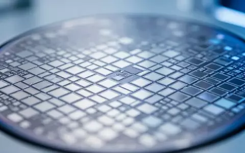 Nahaufnahme eines Silizium-Wafers mit einem präzisen Gitter aus mikroskopischen Spiegelstrukturen unter Laborlicht. - Foto: über boerse-global.de
