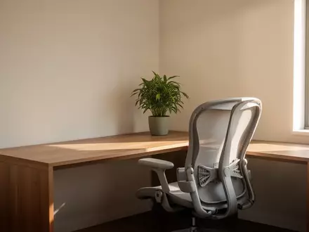 Ein minimalistisch eingerichteter, heller Arbeitsplatz in einem Wohnraum mit einer Pflanze und natürlichem Tageslicht. - Foto: über boerse-global.de