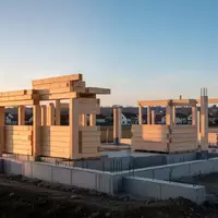 Eine Baustelle mit Holz- und Betonelementen für ein neues Wohngebiet in einer ländlichen Umgebung bei Sonnenuntergang. - Foto: über boerse-global.de