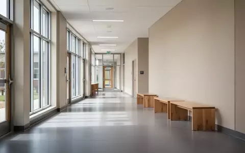 Ein heller, leerer Schulflur mit moderner Architektur und einfallendem Tageslicht. - Foto: über boerse-global.de