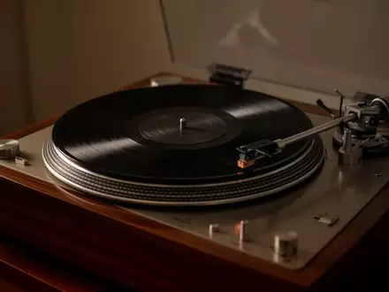 Ein hochwertiger Plattenspieler mit einer rotierenden Vinylschallplatte in einem ruhig beleuchteten Raum. - Foto: über boerse-global.de