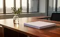 Ein minimalistisch gestalteter, heller Büroraum mit einem Holztisch, einer kleinen Pflanze und natürlichem Tageslicht. - Foto: über boerse-global.de