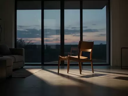 Ein leerer Stuhl in einem modern eingerichteten Wohnzimmer bei Dämmerlicht, der eine Atmosphäre der Isolation und des Verlusts vermittelt. - Foto: über boerse-global.de