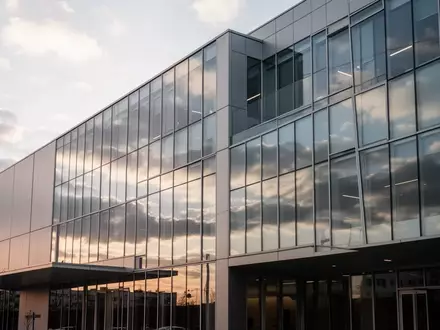 Moderne Glasfassade eines Bankgebäudes unter bewölktem Himmel am Nachmittag. - Foto: über boerse-global.de