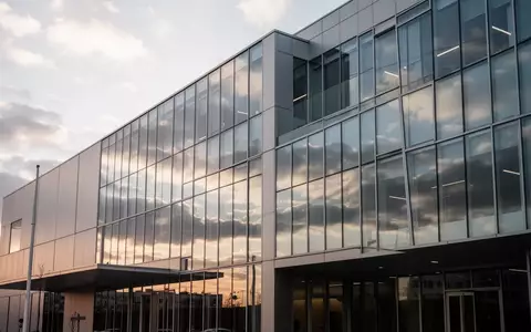 Moderne Glasfassade eines Bankgebäudes unter bewölktem Himmel am Nachmittag. - Foto: über boerse-global.de
