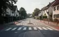 Eine leere, ruhige Straße in einem Wohngebiet mit Fußgängerüberweg und Verkehrsberuhigung bei Tageslicht. - Foto: über boerse-global.de
