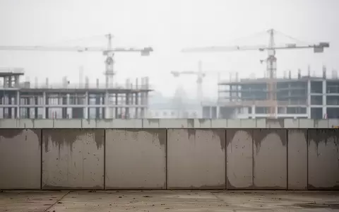 Eine leere Baustelle in Wien vor einem bewölkten Himmel mit Kränen im Hintergrund. - Foto: über boerse-global.de
