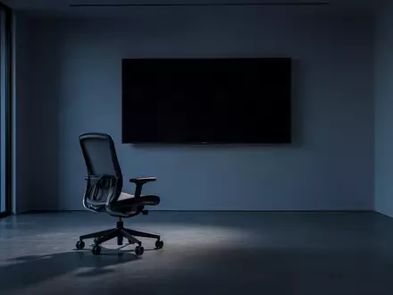 Ein minimalistisch eingerichteter, dunkler Büroraum mit einem leeren Schreibtisch und einem inaktiven Monitor in der Dämmerung. - Foto: über boerse-global.de