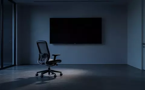 Ein minimalistisch eingerichteter, dunkler Büroraum mit einem leeren Schreibtisch und einem inaktiven Monitor in der Dämmerung. - Foto: über boerse-global.de