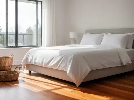 Ein helles, modern eingerichtetes Wohnzimmer mit einem frisch bezogenen Bett und einem Korb auf dem Boden bei Tageslicht. - Foto: über boerse-global.de