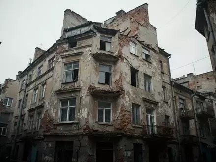 Fassade eines baufälligen Wohnhauses in einer städtischen Umgebung bei bewölktem Himmel. - Foto: über boerse-global.de