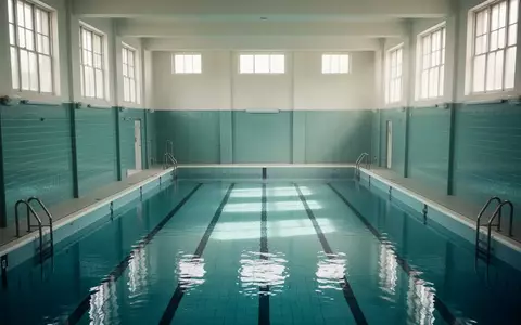Ein leeres, gefliestes städtisches Schwimmbecken in einem hellen, architektonisch schlichten Gebäude bei Tageslicht. - Foto: über boerse-global.de