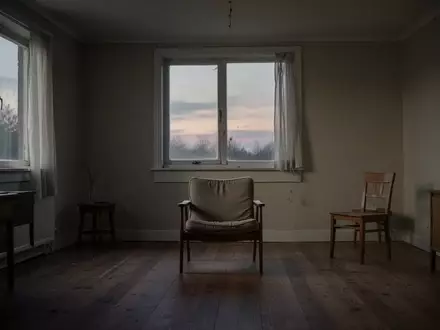 Ein minimalistisch eingerichtetes, leeres Wohnzimmer in der Dämmerung mit einem einzelnen Sessel am Fenster. - Foto: über boerse-global.de