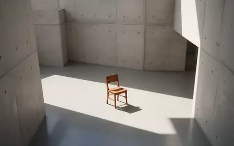 Ein minimalistischer, lichtdurchfluteter Raum mit klaren architektonischen Linien und einem einzelnen leeren Stuhl. - Foto: über boerse-global.de