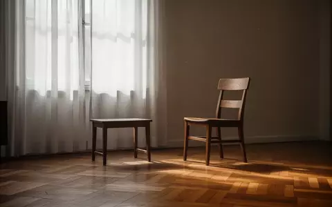 Ein heller, ruhiger Wohnraum mit einem leeren Stuhl vor einem Fenster, das sanftes Tageslicht einfallen lässt. - Foto: über boerse-global.de