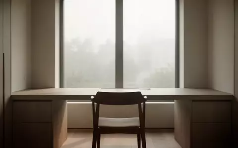 Ein minimalistischer, ruhiger Arbeitsplatz mit einem leeren Stuhl vor einem Fenster mit weichem Tageslicht. - Foto: über boerse-global.de
