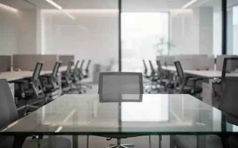 Ein minimalistisch gestalteter, leerer Büroarbeitsplatz mit einem modernen Konferenztisch und gedämpftem Licht. - Foto: über boerse-global.de