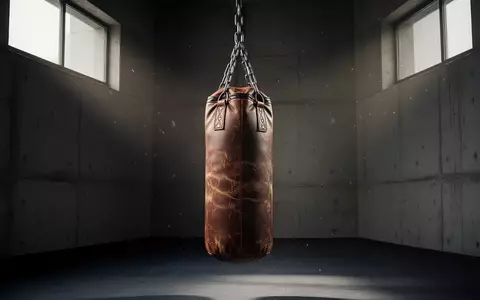Ein schwerer Boxsack aus Leder hängt in einem leeren, schlichten Trainingsraum mit Betonwänden. - Foto: über boerse-global.de