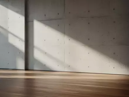 Ein moderner, minimalistischer Innenraum mit klaren Linien und weichem Lichteinfall auf einer Betonwand. - Foto: über boerse-global.de