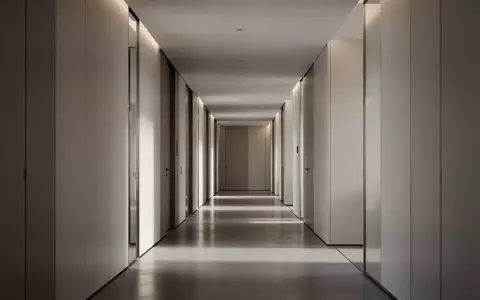 Ein minimalistischer, moderner Büroflur mit klaren architektonischen Linien und indirekter Beleuchtung ohne Personen. - Foto: über boerse-global.de