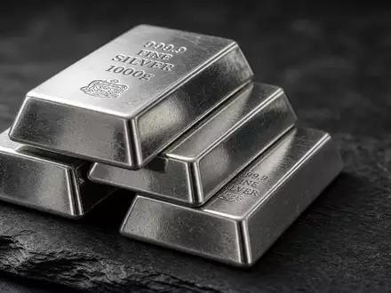 Glänzende Silberbarren gestapelt auf einer dunklen Schieferplatte bei natürlichem, weichem Licht. - Foto: über boerse-global.de