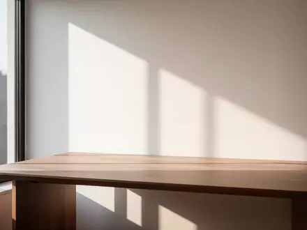 Ein minimalistischer Arbeitsplatz mit einem leeren Holztisch und natürlichem Sonnenlicht, das durch ein Fenster fällt. - Foto: über boerse-global.de