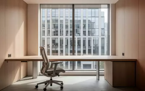 Ein minimalistischer, moderner Arbeitsplatz in einem hellen Büro mit Blick aus dem Fenster auf ein Gebäude. - Foto: über boerse-global.de