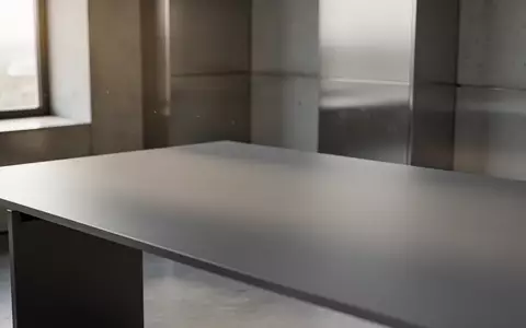 Ein minimalistischer Arbeitsbereich mit einem leeren, matten Schreibtisch in sanftem Tageslicht vor einer modernen Architektur. - Foto: über boerse-global.de