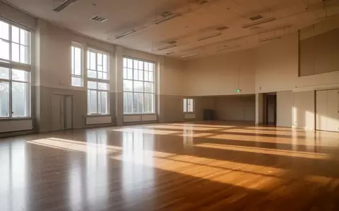 Ein heller, leerer Mehrzweckraum in einem Gemeindezentrum mit Holzboden und großen Fenstern bei Tageslicht. - Foto: über boerse-global.de