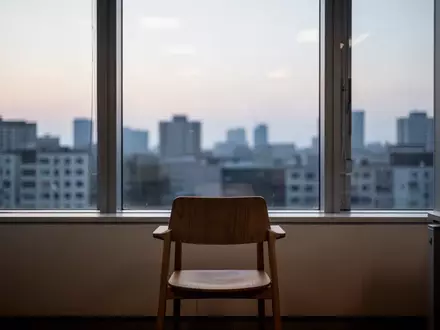 Ein ruhiges, minimalistisches Büro mit einem leeren Stuhl vor einem Fenster mit Blick auf eine abendliche Stadtkulisse. - Foto: über boerse-global.de