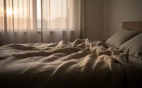 Ein minimalistisches, ruhiges Schlafzimmer bei Tagesanbruch mit weichem, natürlichem Licht, das auf ein ungemachtes Bett fällt. - Foto: über boerse-global.de