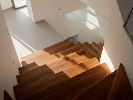 Eine minimalistische Treppe in einem hellen, modernen Gebäude mit klaren Linien und natürlichem Lichteinfall. - Foto: über boerse-global.de