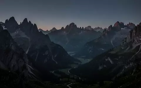 Eine weite, ruhige Berglandschaft in der Abenddämmerung mit scharfen Felsformationen und tiefen Schatten unter einem klaren Himmel. - Foto: über boerse-global.de
