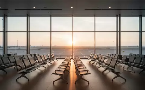 Leere, lichtdurchflutete Abflughalle eines Flughafens mit Blick auf das Rollfeld bei Sonnenaufgang. - Foto: über boerse-global.de