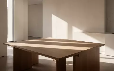 Ein sonnendurchfluteter, minimalistischer Raum mit klaren architektonischen Linien und weichem Tageslicht auf einem Holztisch. - Foto: über boerse-global.de