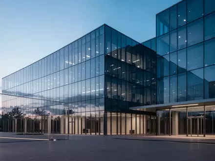 Ein modernes, minimalistisches Bürogebäude bei Dämmerung, das die blaue Atmosphäre des Himmels reflektiert. - Foto: über boerse-global.de
